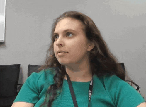 a woman in a green shirt has a lanyard around her neck that says " maker "