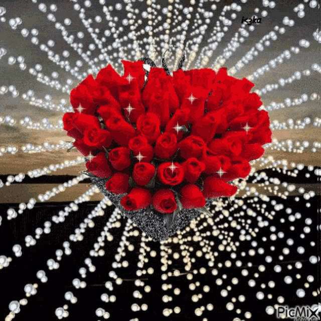 a heart shaped bouquet of red roses is surrounded by pearls .