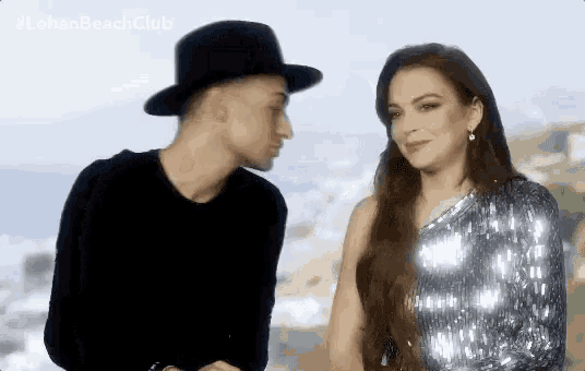 a man in a hat is kissing a woman in a sequined dress