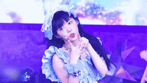 a girl wearing a blue dress and a purple hat is standing on a stage .