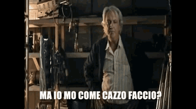 a man in a suit is standing in a room with the words ma io mo come cazzo faccio