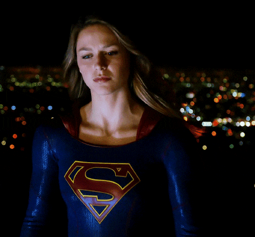 a woman in a superman costume stands in front of a city at night