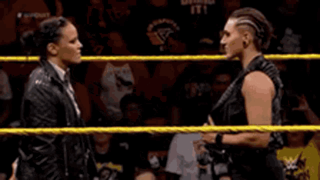 two women are shaking hands in a wrestling ring while talking to each other .