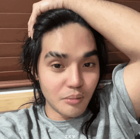 a man with long hair is wearing a grey shirt that says zky on it