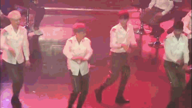 a group of men in white shirts are dancing on a stage .