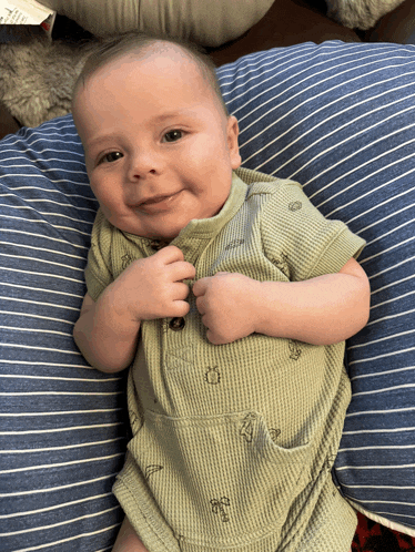 a baby is laying on a striped pillow and smiling for the camera