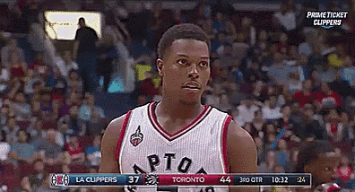 a man in a toronto raptors jersey stands in front of a crowd during a basketball game
