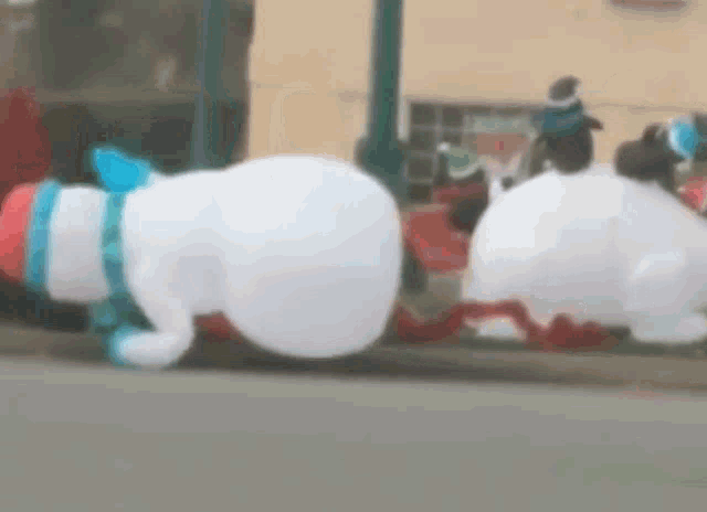 a couple of inflatable snowmen are doing push ups on the side of the road .