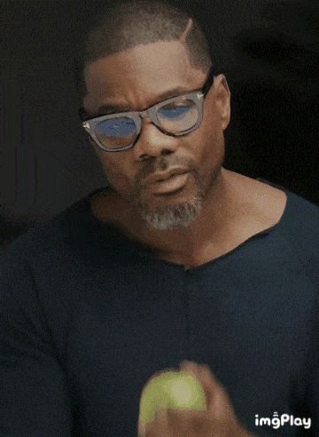 a man wearing glasses and a blue shirt is holding a green apple