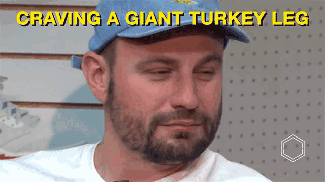 a man with a beard wearing a blue hat and a white shirt says craving a giant turkey leg