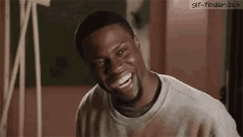 a man with a beard is laughing while wearing a gray sweater .