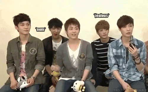 a group of young men are sitting next to each other and one of them is holding a hello kitty toy