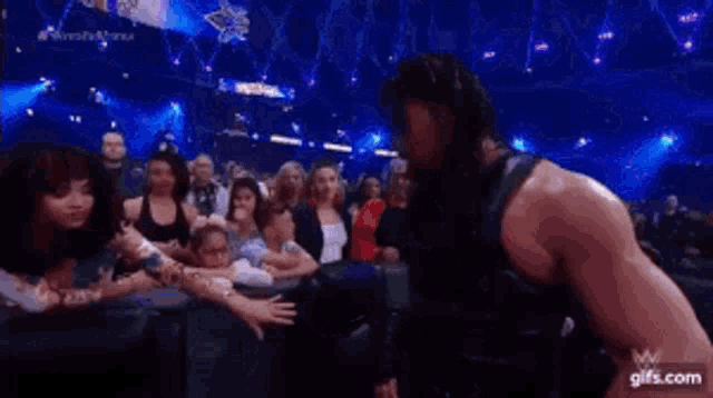 roman reigns is standing in front of a crowd of people .