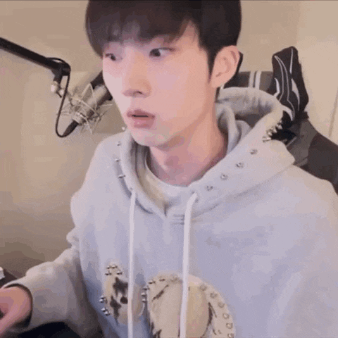 a young man in a hoodie is sitting in front of a microphone in a room .