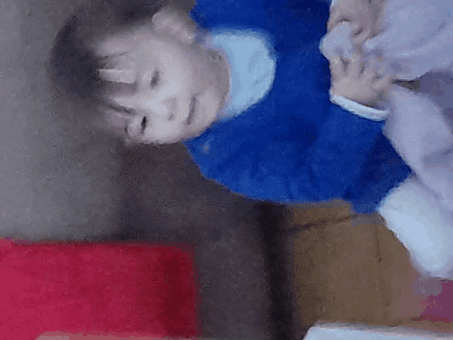 a child in a blue sweater is laying on its back