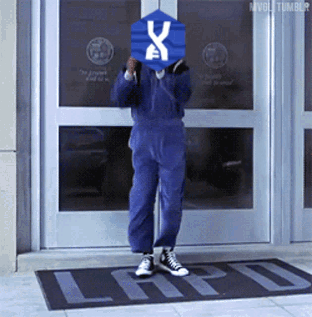 a person in a blue jumpsuit is standing in front of a door that says lad