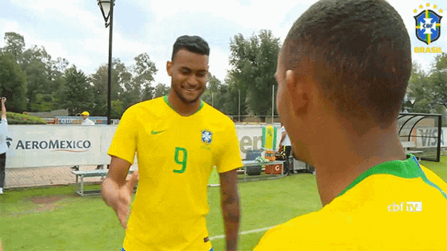 two soccer players are shaking hands in front of a banner for aeromexico