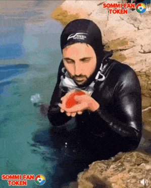 a man in a wet suit is holding something in his hands with sommi fan token written on the bottom right
