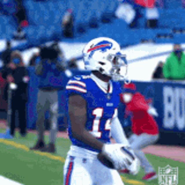 a football player in a buffalo bills uniform is holding a football .