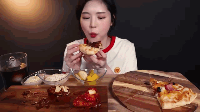 a woman is eating a slice of pizza on a wooden board .