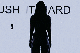 a silhouette of a woman standing in front of a sign that says push it hard