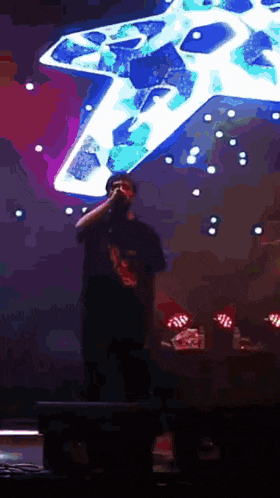 a man singing into a microphone on a stage in front of a large star