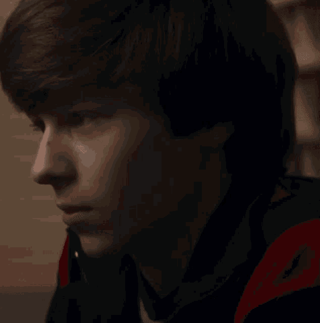 a close up of a young man 's face with a red and blue jacket on .