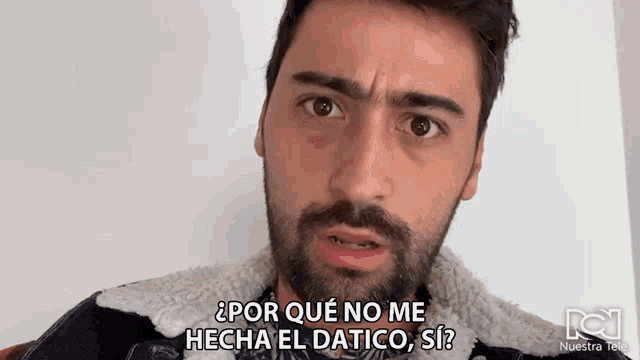 a man with a beard is wearing a denim jacket and says por que no me hecha el datico si ?