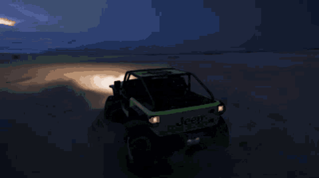a green jeep is driving through a desert at night