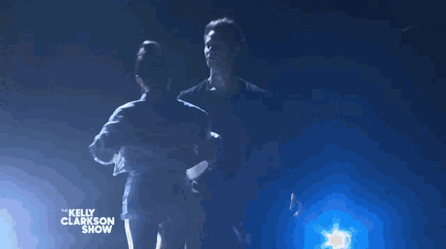 a couple dancing on the kelly clarkson show in a dark room