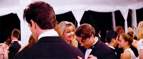 a man in a tuxedo is dancing with a woman in a black dress