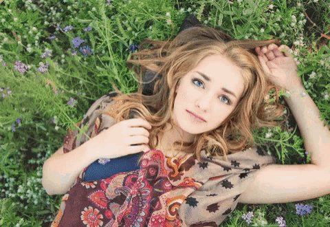 a woman laying in a field of flowers with a book