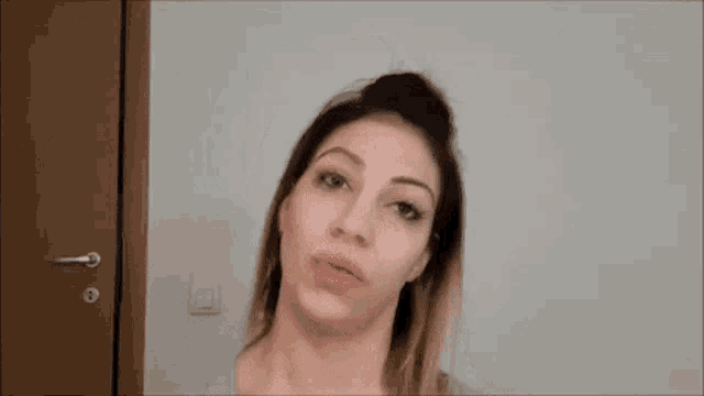 a woman with her hair in a bun is making a funny face .