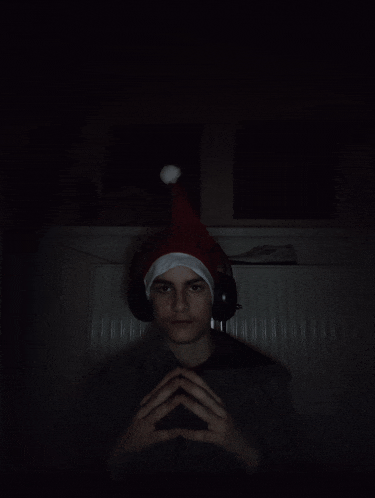 a man wearing headphones and a santa hat looks at the camera