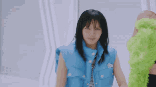 a girl in a blue jacket is holding a green object in her hand