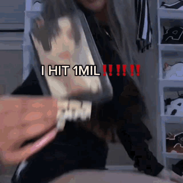 a woman is holding a phone in her hand and says i hit 1 mil !!!