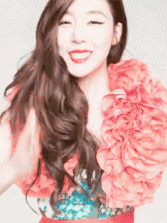 a woman with long hair is wearing a pink top with ruffles