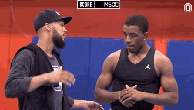 two men are standing next to each other with a score of 14500 in the background