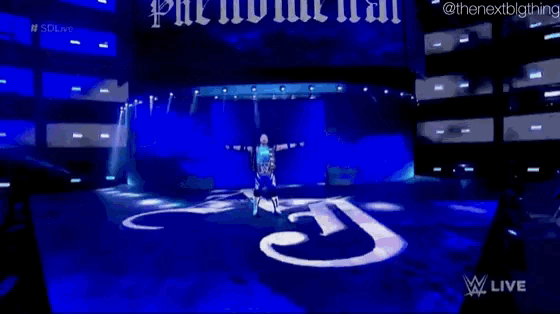 a wrestler is standing on a stage in front of a large j on the floor .