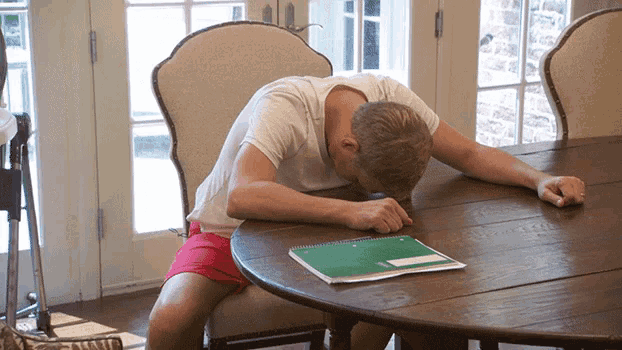 a man sits at a table with his head on a notebook