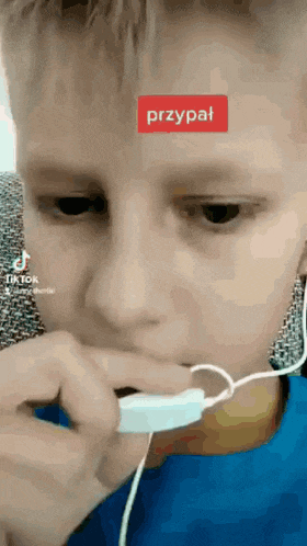 a young boy wearing headphones and a blue shirt has a tiktok sticker on his forehead that says przypat