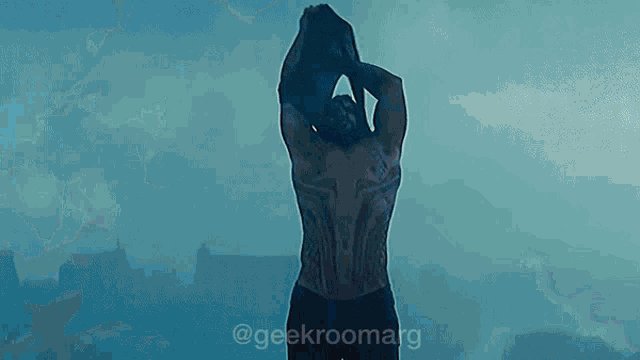 a man without a shirt is walking in the rain with a picture of him taken by @geekroomarg