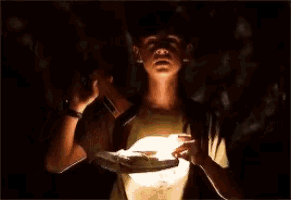 a young boy is holding a flashlight in his hand in the dark .