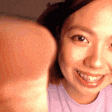 a woman in a purple shirt is smiling and giving a thumbs up sign .