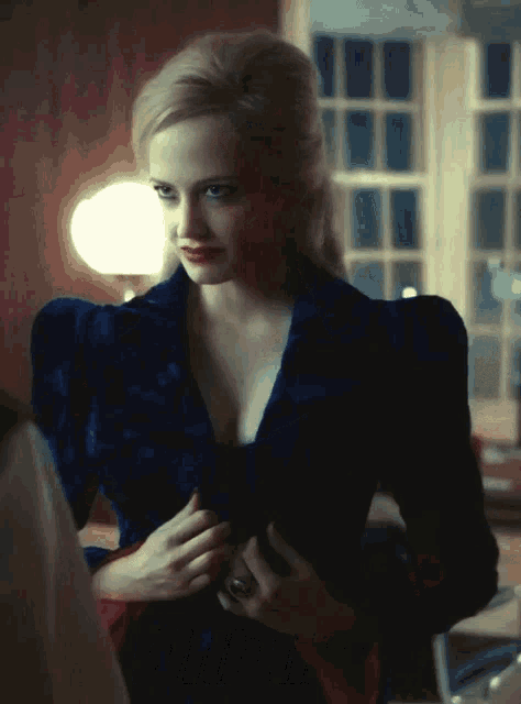 a woman in a blue velvet jacket is standing in a room