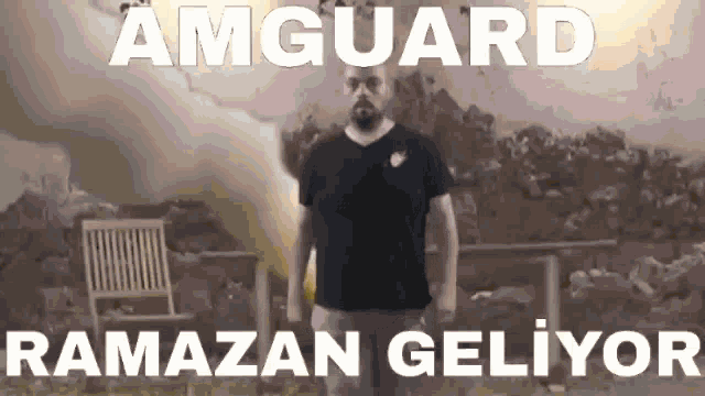 a man in a black shirt is standing in front of a chair with the words amguard ramazan geliyor written on it