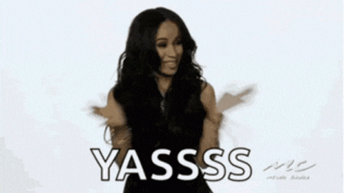 a woman in a black dress is standing in front of a white background and says yasss .