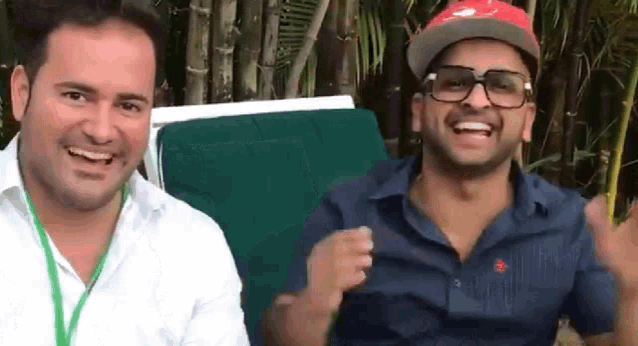 two men are sitting next to each other and smiling for the camera .