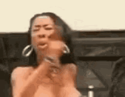 a woman without a shirt is making a funny face while wearing earrings .
