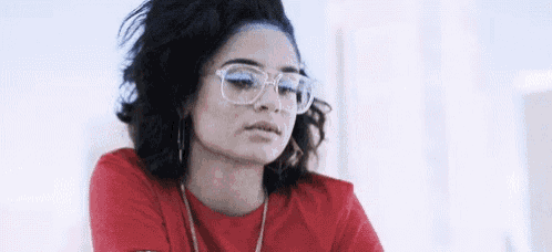 a woman wearing glasses and a red t-shirt is looking at the camera .